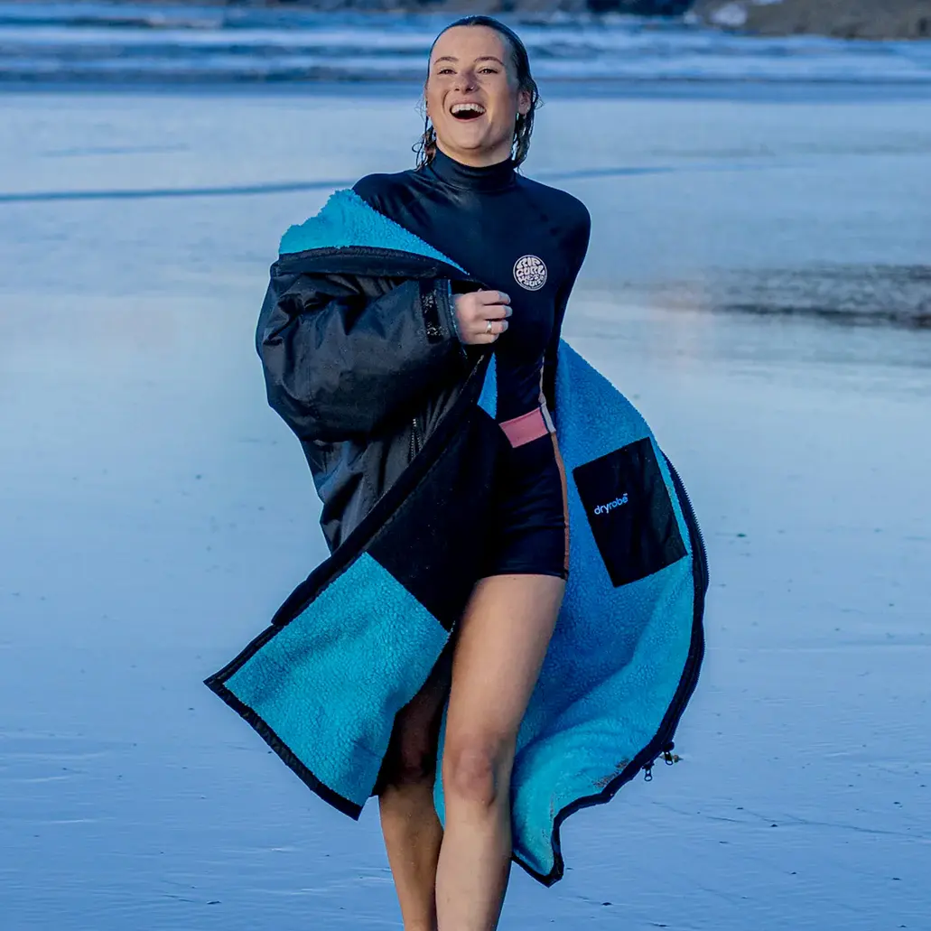 Surfer woman wearing a Dryrobe Advance Changing Robe after a surf session