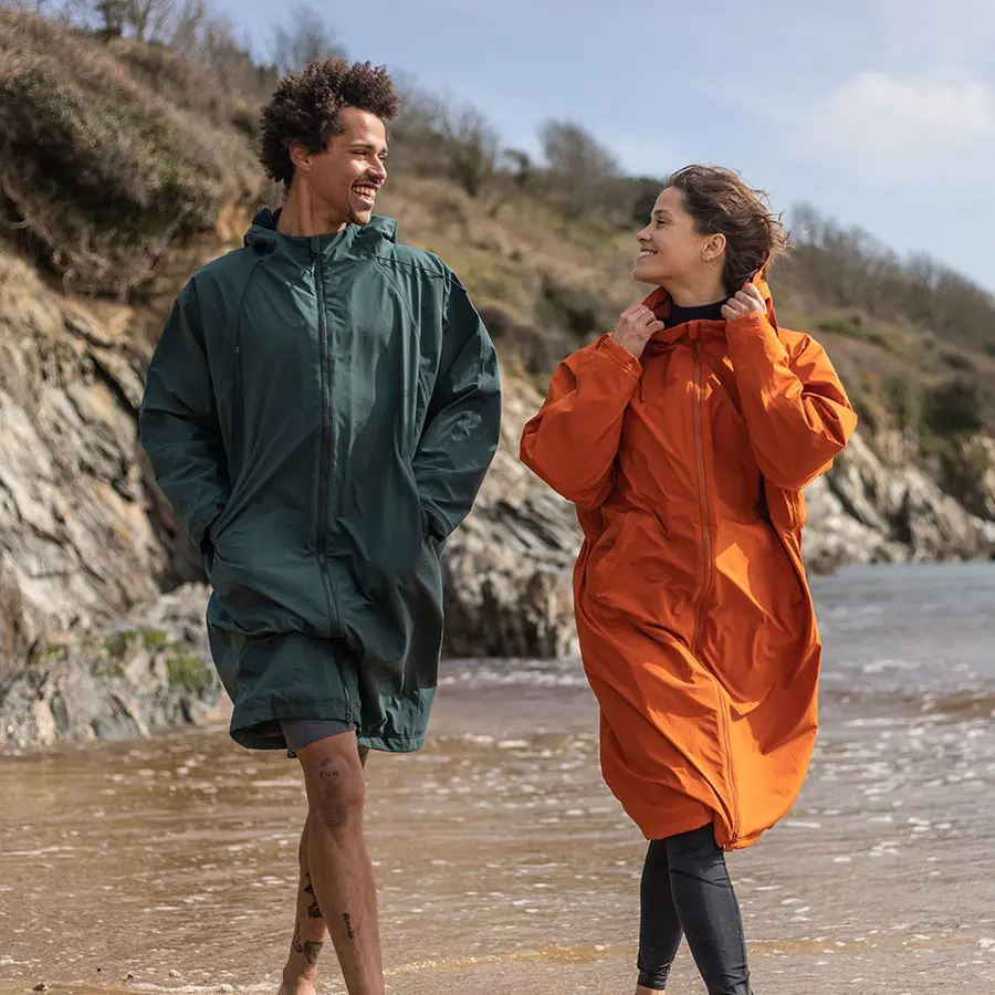 Man and woman walking on the beach in Fourth Element Tidal Robes