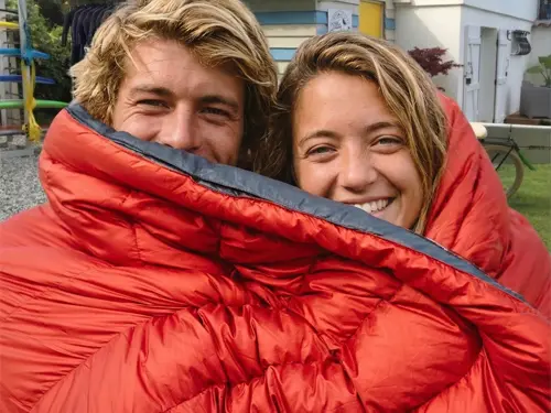 Young couple wrapped in a Kammok Firebelly Trail Quilt