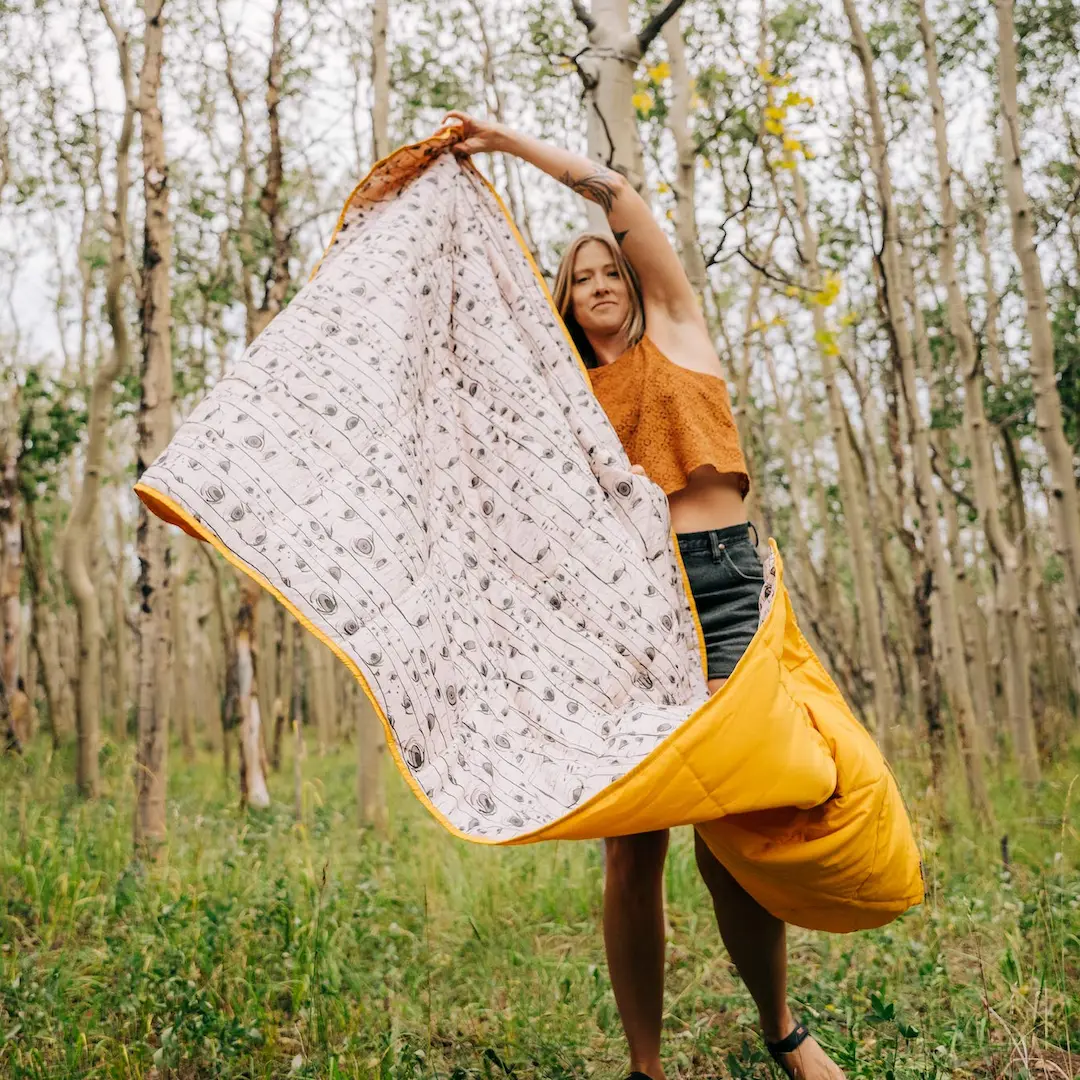Young woman holding a Kelty Bestie blanket above her head