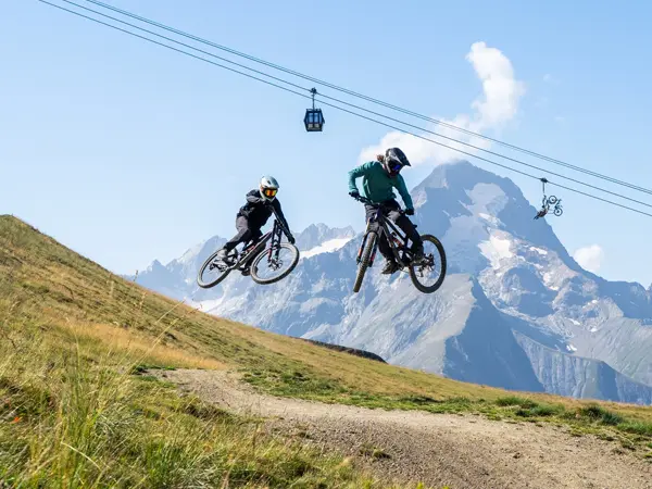 Mountain bikers hitting a jump in Les 2 Alpes bikepark