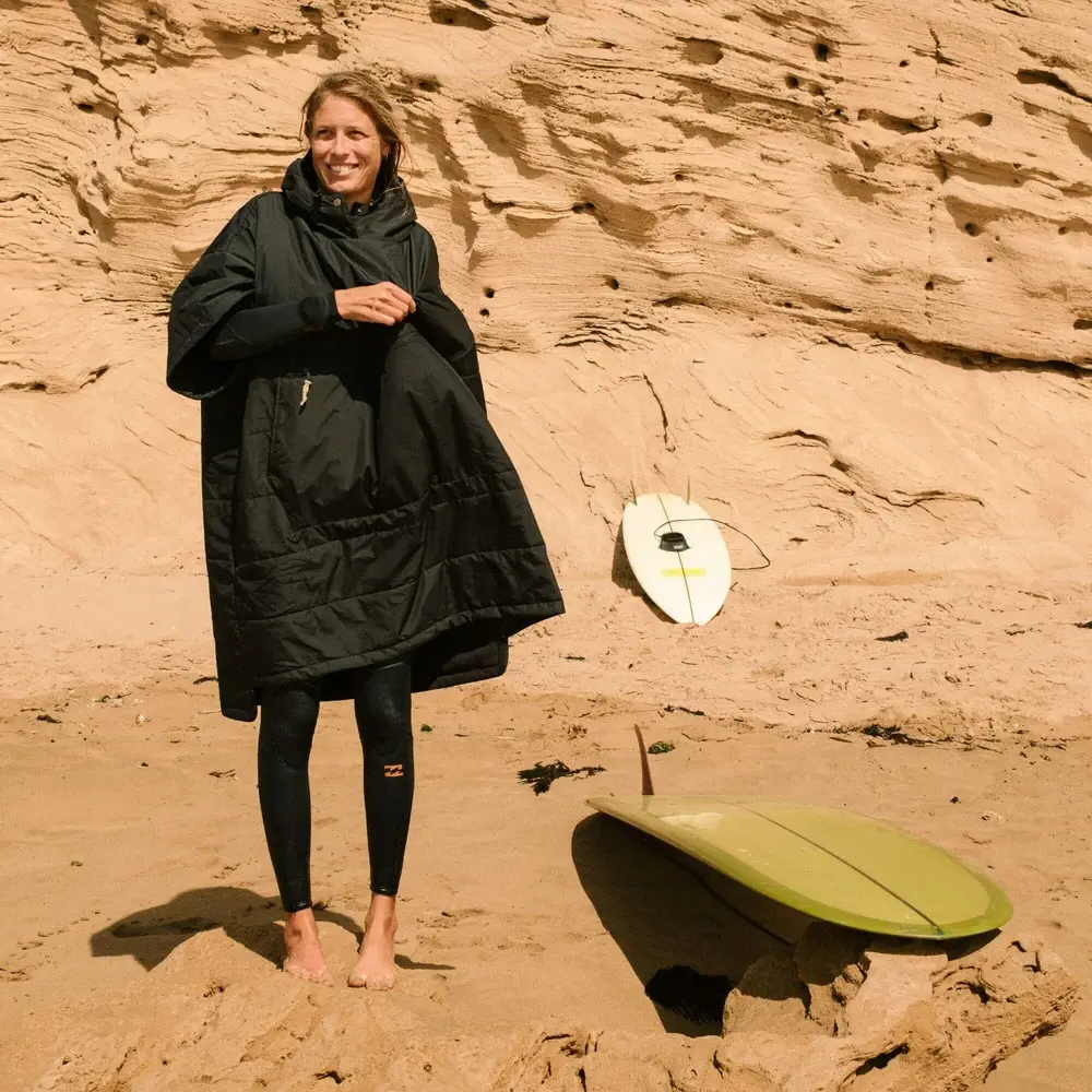 Surfer changing into her wetsuit whilst wearing a VOITED Outdoor Poncho 3.0