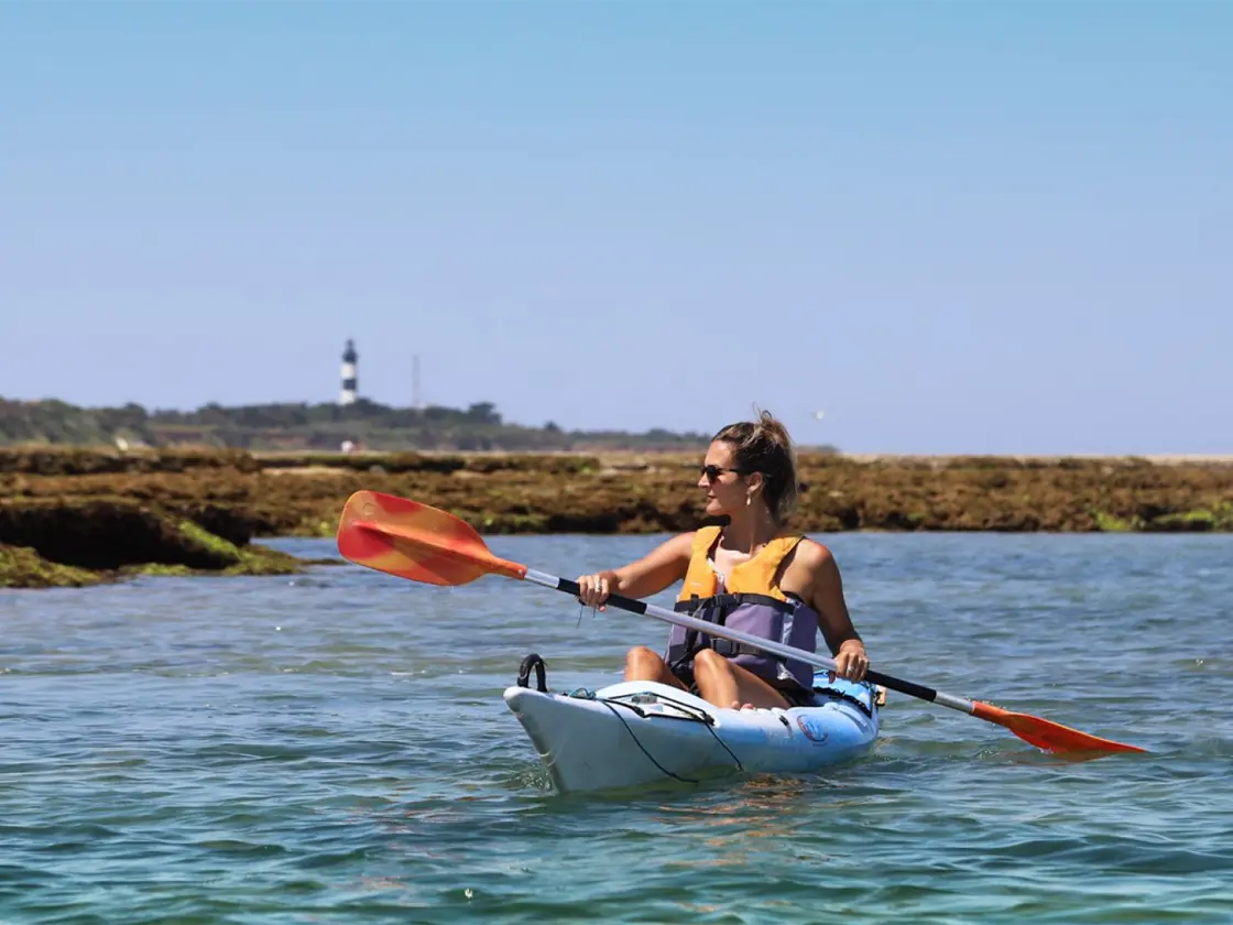 Woman wearing a yellow lifejacket sea kayaking on the Île d'Oléron