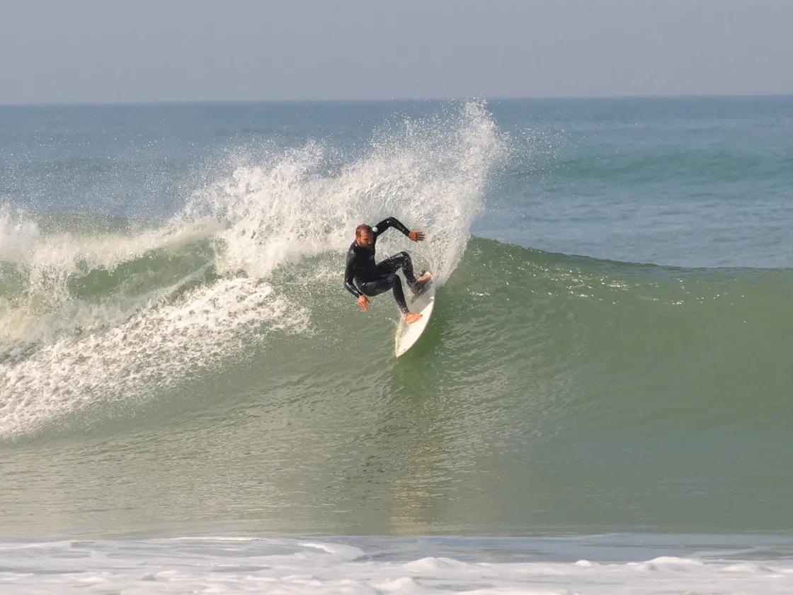 A surfer rides a mellow wave at Pontaillac beach in Royan